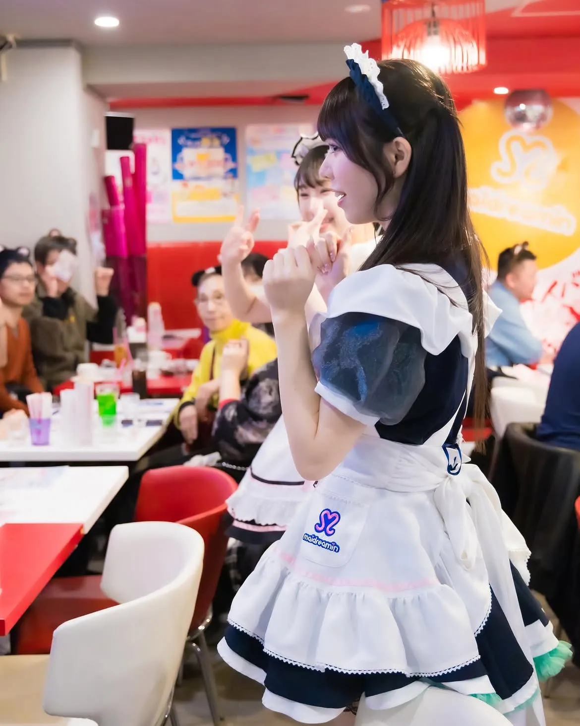 メイドカフェのキャストと一緒にポーズをとる参加者